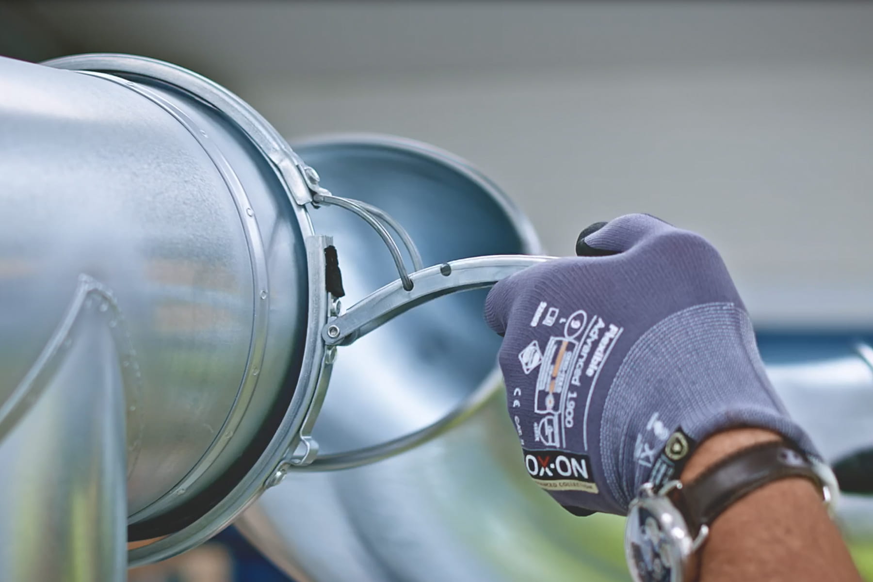Close-up of man installing Nordfab ducting using a clamp.
